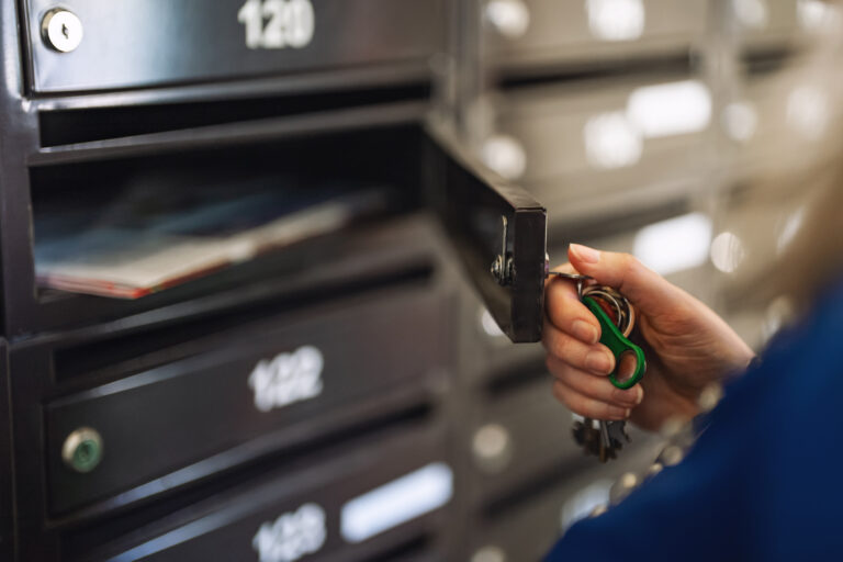 Woman checking mailbox in apartment building.